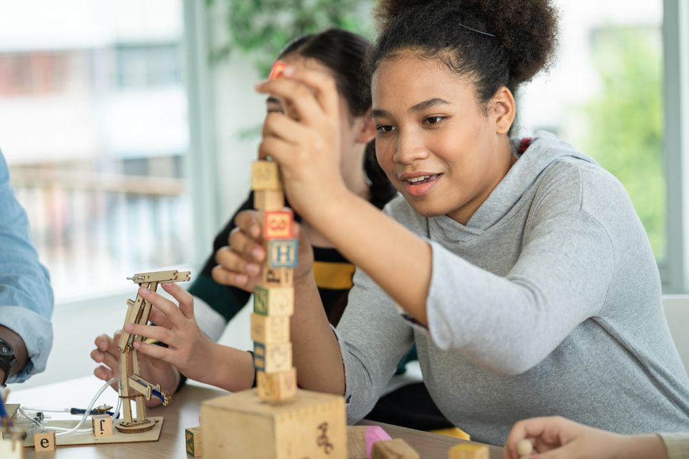 Girl creating pile of blocks on table