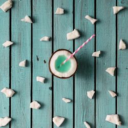 Coconut half with straw pattern on blue wooden background