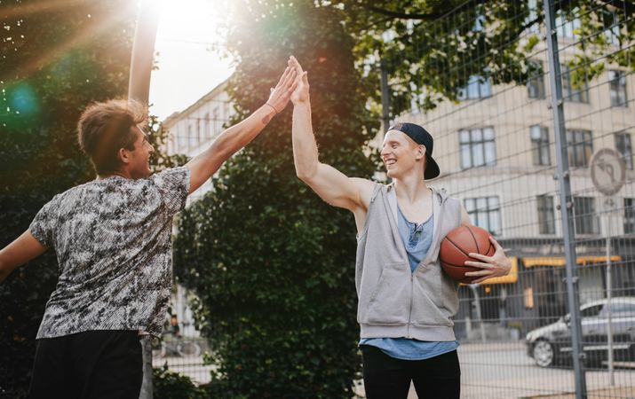 Friends giving high five after a game of streetball