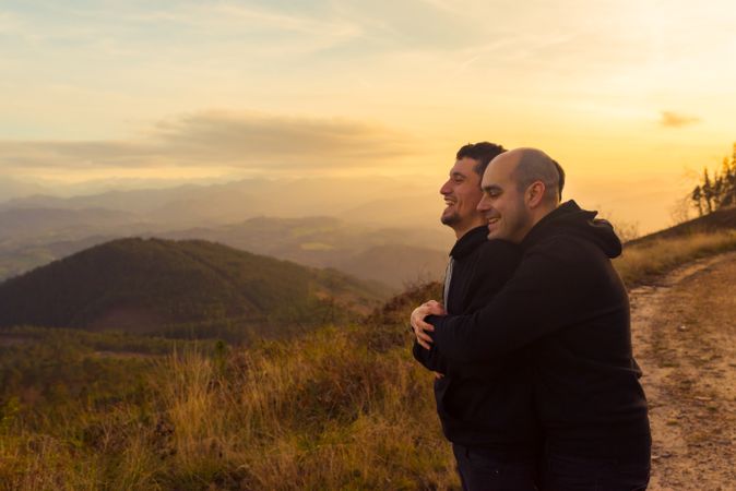 Men hugging on road on hill