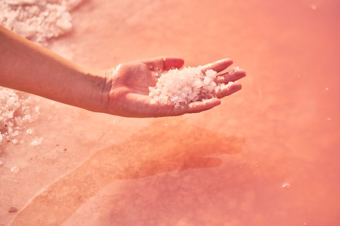 Female holding healing salt pile in pink water