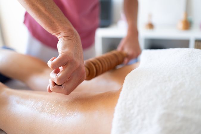 Masseuse working on hamstrings of female client in spa