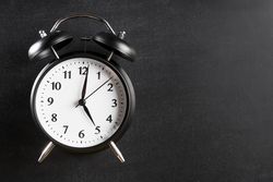 Alarm clock showing 5 o’clock against a dark background