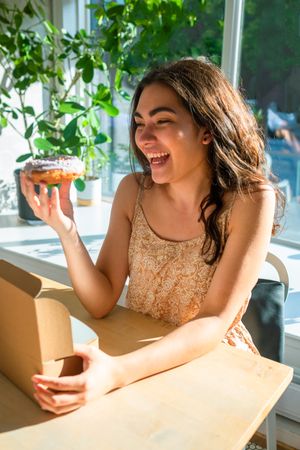 Woman enjoying tasty donut in cafe