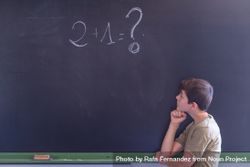 Boy standing at board with math question written in chalk 4NR7l4