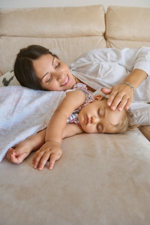 Happy woman with kid lying on sofa