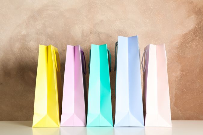 Color bags on table against brown background, copy space