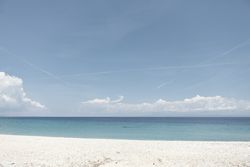 Seascape of white sandy shore and calm water