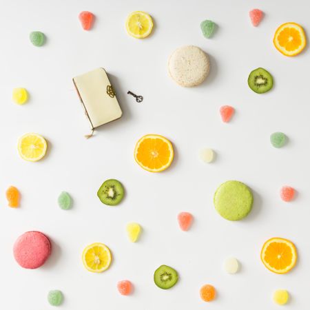 Fruit slices, gummies, and macarons and diary with lock on light background