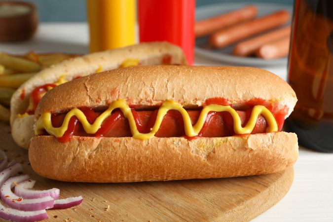 Tasty hot dogs, beer and sauces on plain wooden background