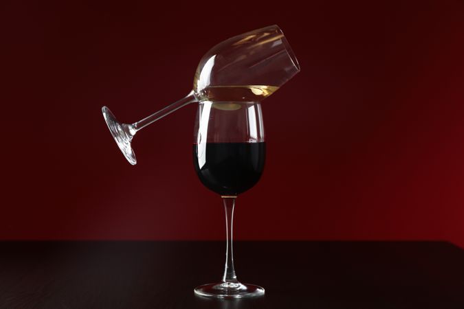 Glasses with wine against red background, copy space
