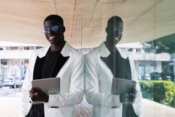 Content Black businessman in stylish apparel with computer outdoors