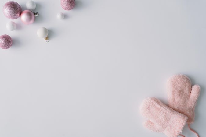 Pink baubles and mittens in corners of light background
