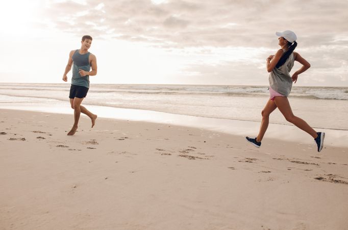 Young man and woman running in morning on beach