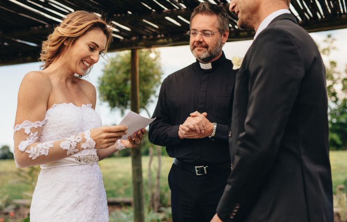 Woman read vows from paper for her husband at wedding ceremony background