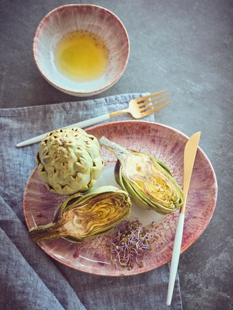 Tasty artichokes near bowl of oil