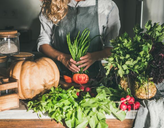 Blonde woman holding long beans  in rustic kitchen