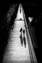 Grayscale photo of two people walking on sidewalk