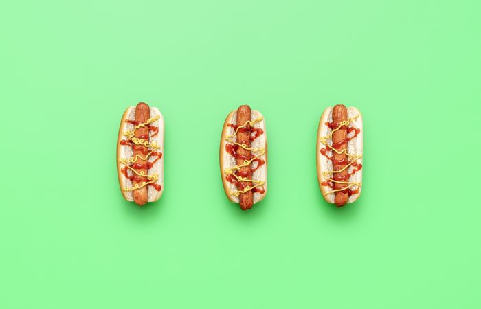 Barbecued hot dogs with ketchup and mustard over bright green background