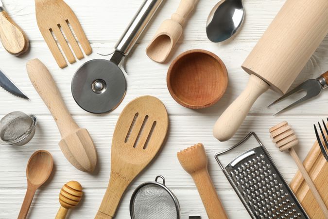 Different kitchen cutlery on wooden background
