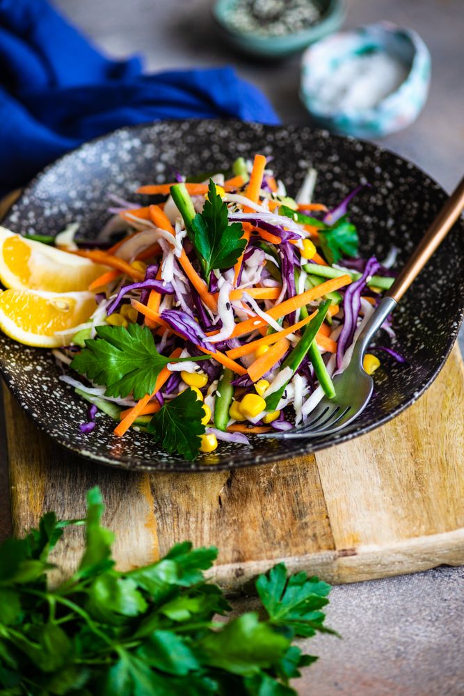 Fresh salad with finely chopped vegetables and lemon slices in bowl with copy space