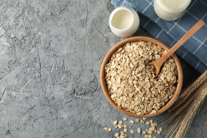 Composition with oatmeal flakes on gray background. Cooking breakfast