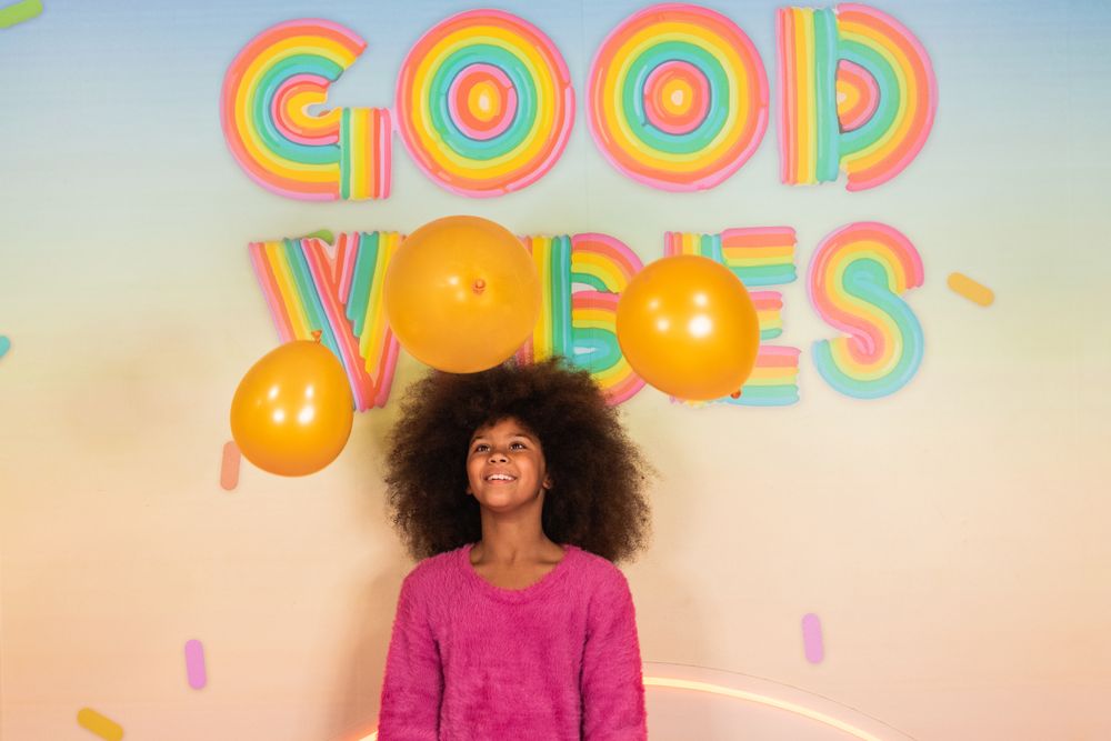 Cheerful Black girl with air balloons in studio