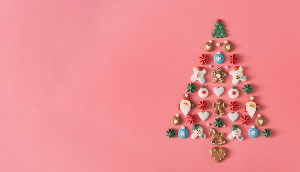 Festive tree made out of holiday cookies on salmon background