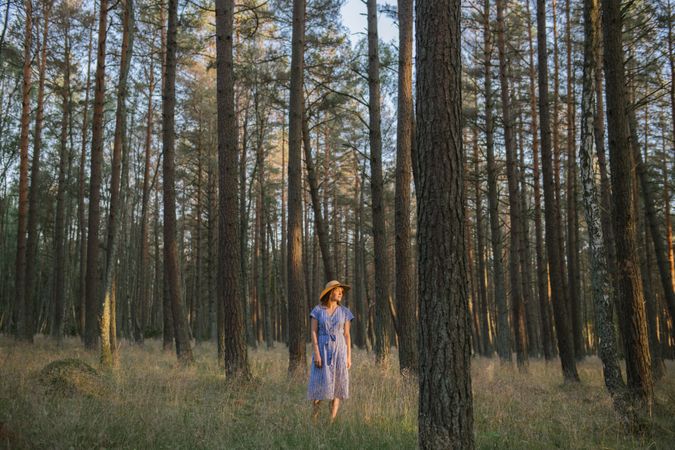 Young woman standing among pine trees