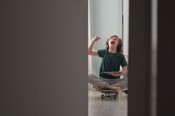 Expressive boy sitting on skateboard and watching video