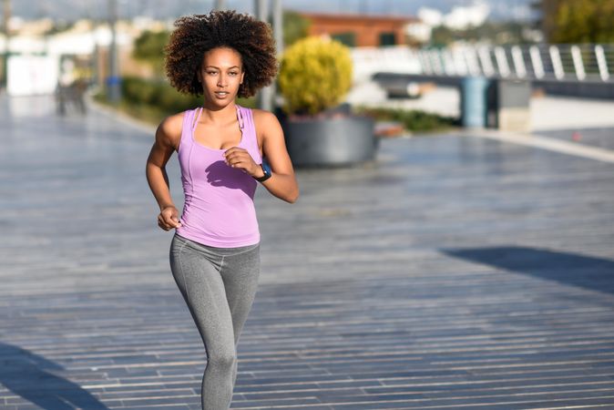 Woman, with afro hairstyle, running outside in city road