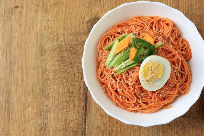 Top view Korean noodle dish plates with boiled egg and fresh vegetables