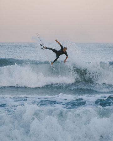 Man surfing on sea waves during sunset