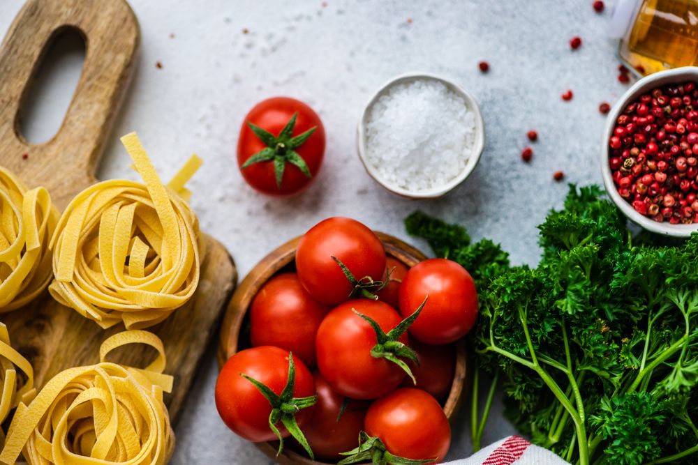 Close up of Fettuccine pasta and fresh vegetables on counter with copy space