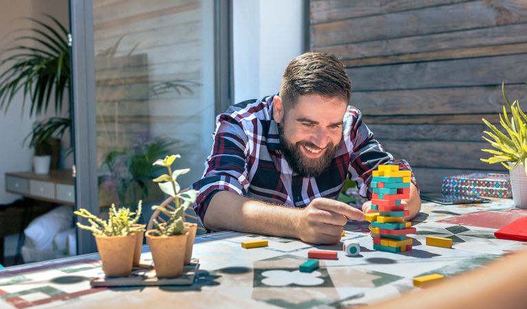 Bearded man catching jenga game piece in rooftop party