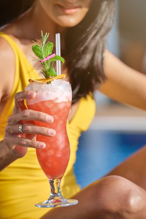 Crop woman with cocktail in glass