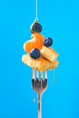 Appetizing fruit dessert with honey on fork