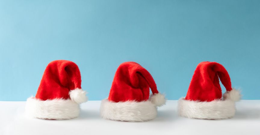 Three Santa Claus hats on blue background