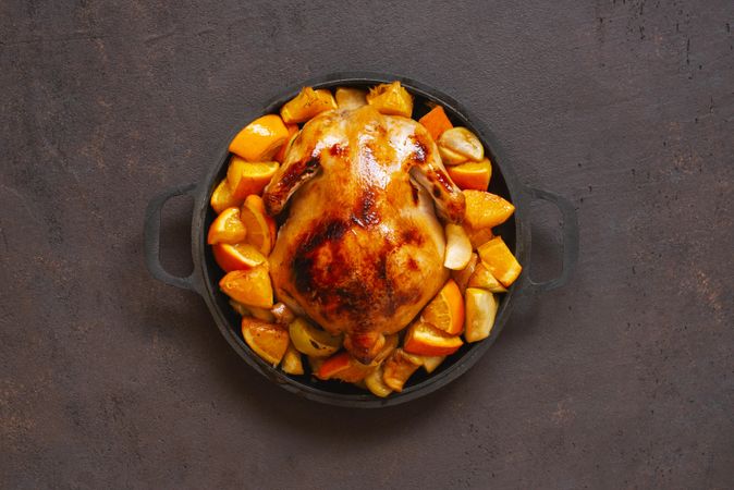 Chicken pot cooked with oranges on dark brown table
