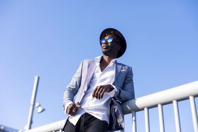 Black man in suit leaning on a bar on a sunny day