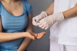 Nurse giving medicine pills to a young female patient