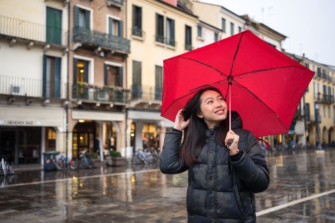 Asian female tourist with umbrella walking at city street on rainy weather