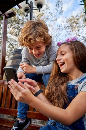 Smiling children sharing smartphone in park