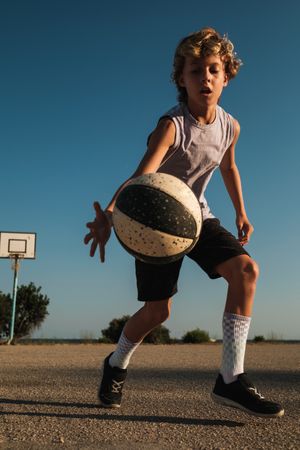 Focused boy in sportswear dribbling basketball