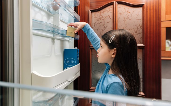 Sad girl taking the last yogurt from the fridge