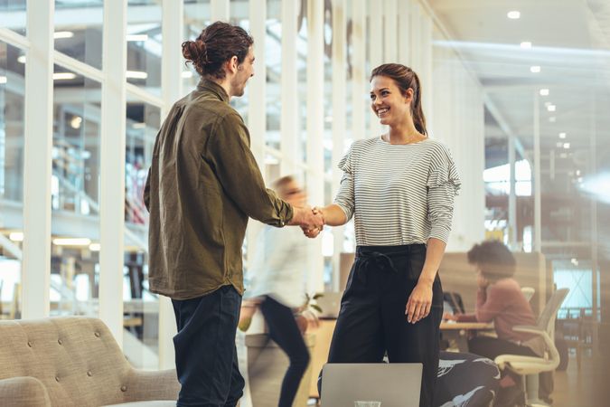 Woman entrepreneur greeting a businessman standing in office