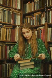 Girl in green polka dress reading a book in library 4Z3NNb