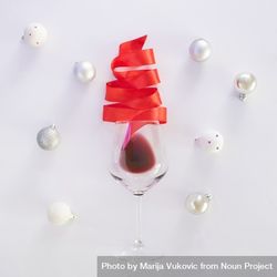Red Christmas tree ribbon coming out of wine glass surrounded by baubles bE1R1b
