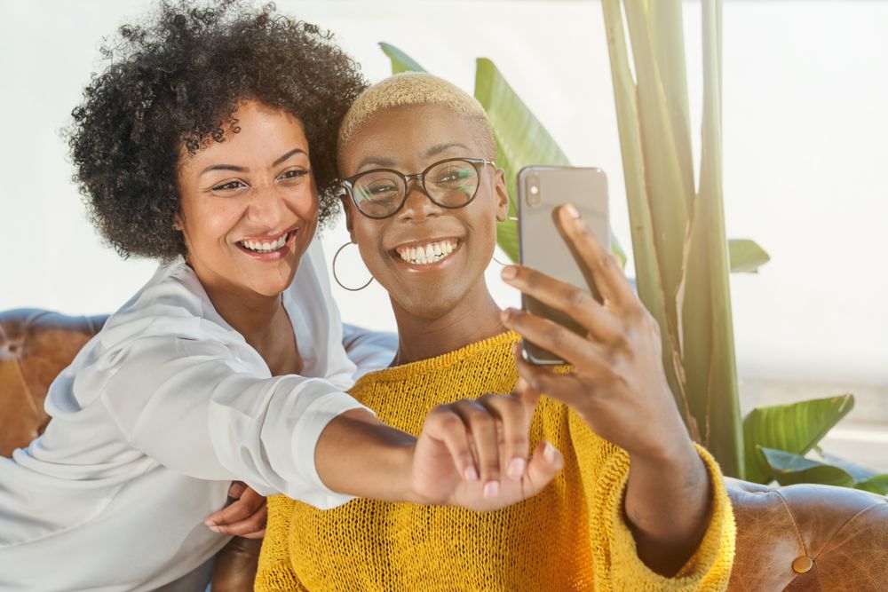 Smiling multiracial women taking selfie on smartphone
