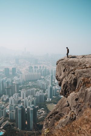 Man standing on cliff over Hong Kong cityscape